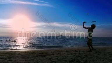 剪影。 人们在日落时在海滩上打羽毛球。